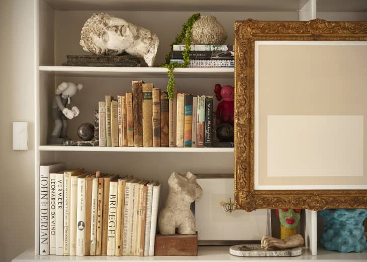 A decorated bookcase with framed art.