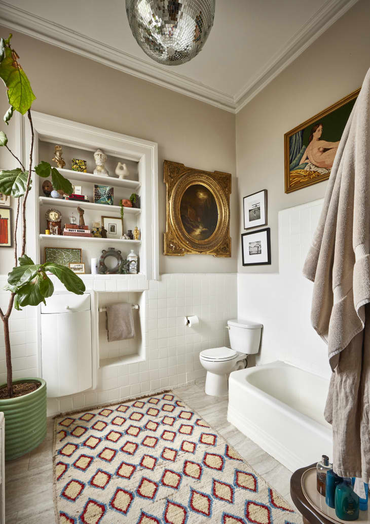 A bathroom with beige walls and decorated shelves.