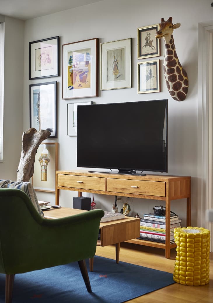 A dinosaur bone next to a large TV and a wooden media center. The white living room also features a green couch.
