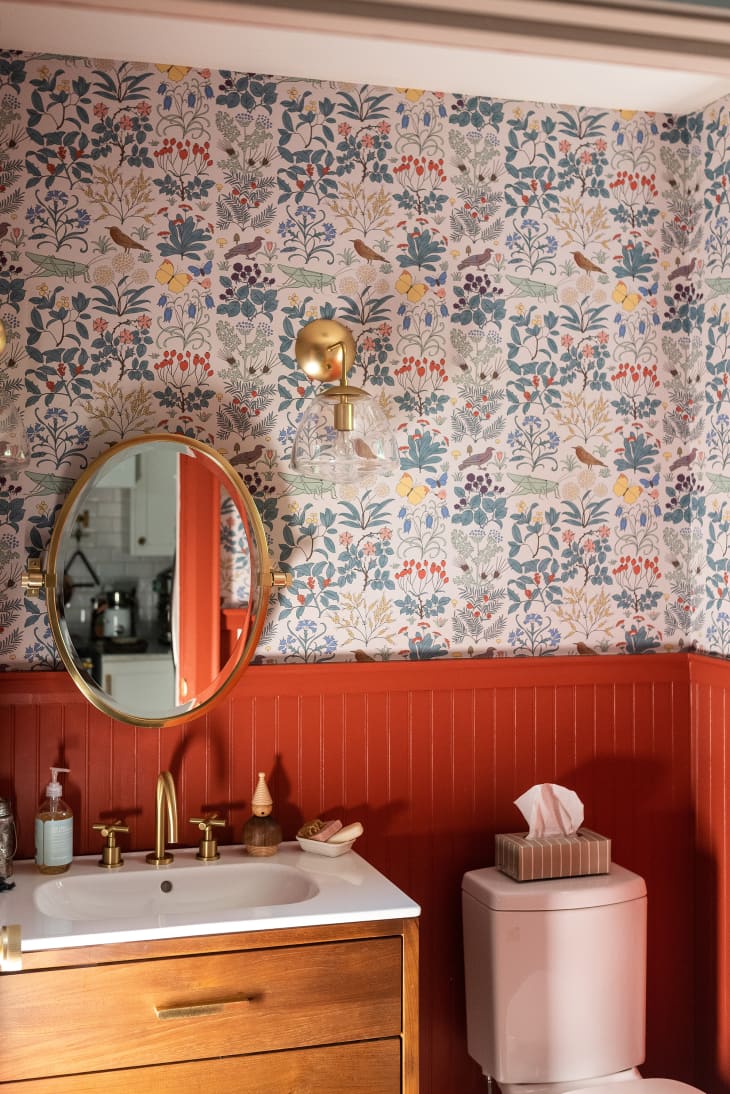 Orange and botanical wallpapered bathroom with wood and gold accents