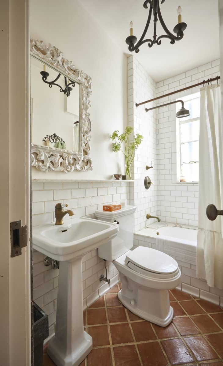 A bathroom room with black tiled walls and a vintage mirror frame.