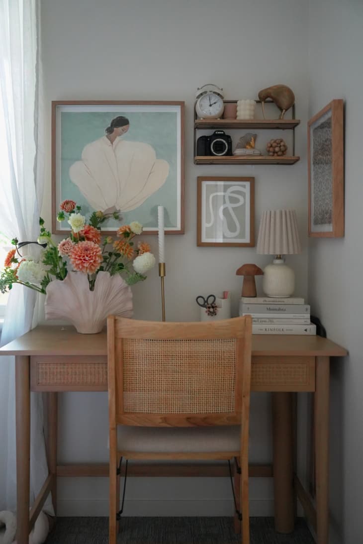 Desk in the corner of a bedroom with a small gallery wall and shelf with decorative items.