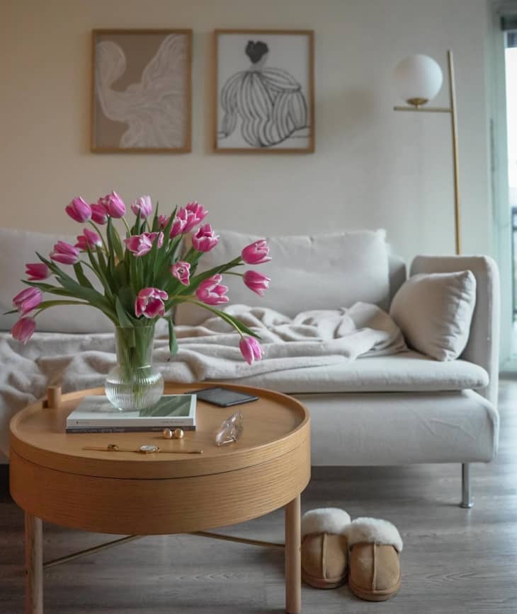 Grey couch with wooden coffee table with floral arrangement.