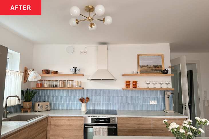 Renovated kitchen with light blue tiled backsplash, light wood cabinets with marble countertops and a kitchen island