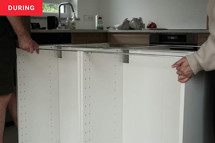 Two people installing kitchen island during a renovation