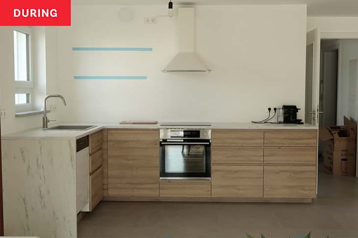 Kitchen during renovation with light wood cabinets and blue tape marking floating shelves