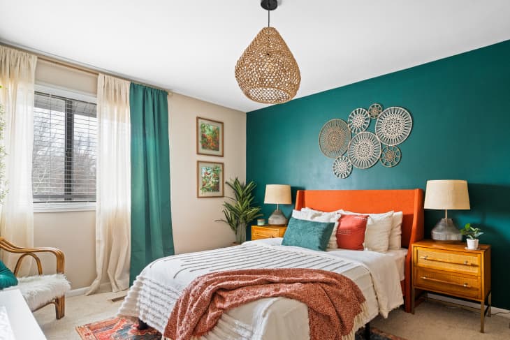 White bedroom with teal accent wall and bed with orange headboard