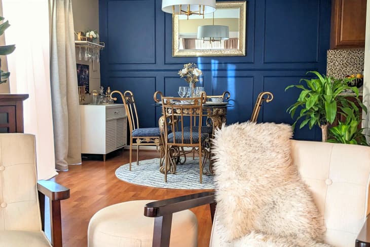 view into dining room with blue wainscoted wall, lyrical metal chairs, and white bar cabinet