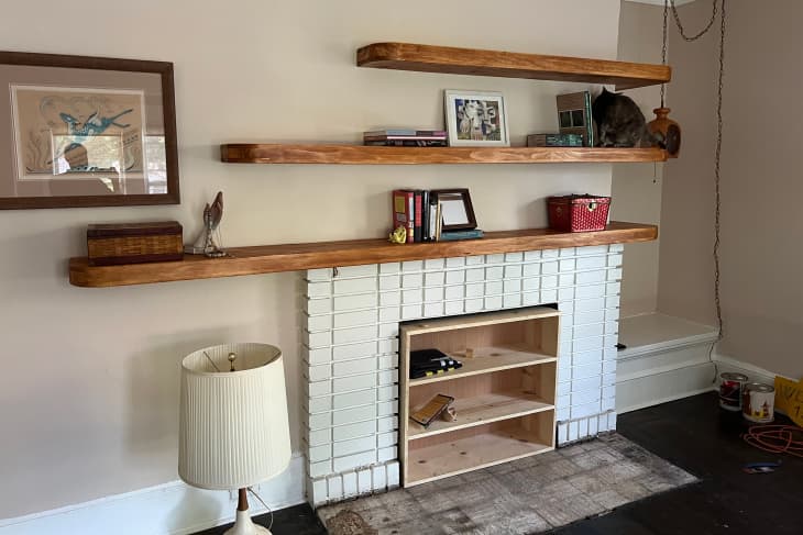 Wooden shelves installed on top of living room fireplace.