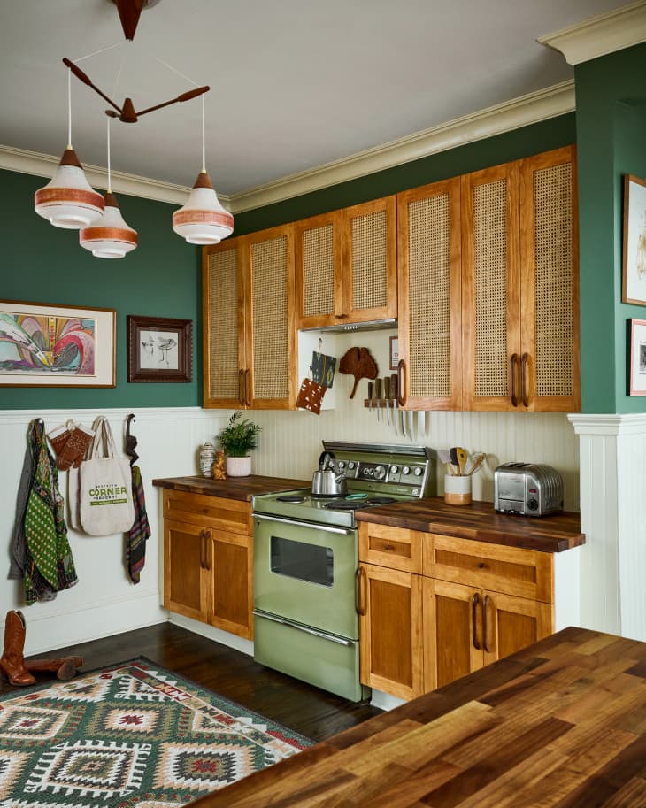 A green kitchen with a vintage green stove and canned wood cabinets.