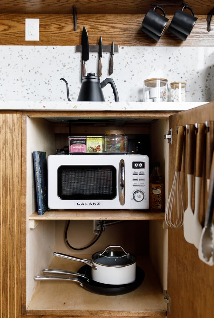 Microwave stored in kitchen cabinet.
