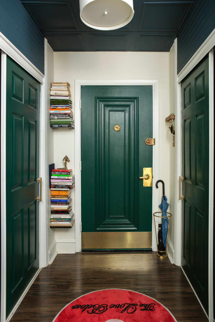 dark teal or green and white entryway/hallway with  floating bookshelves