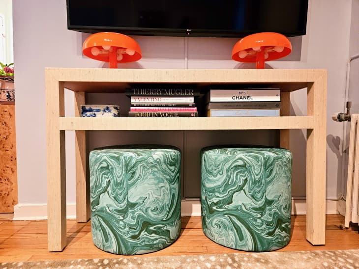 small console table with 2 marbled green ottomans underneath