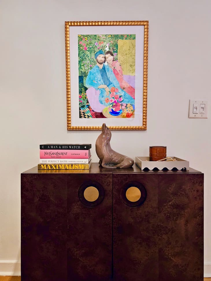 dark wood cabinet with gold round pulls with artwork above