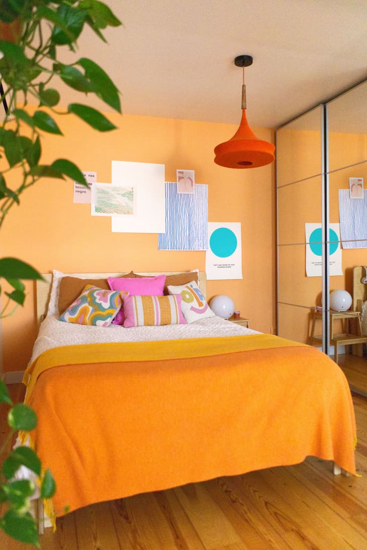 Pale orange bedroom with bright orange pendant light and mirrored closet doors