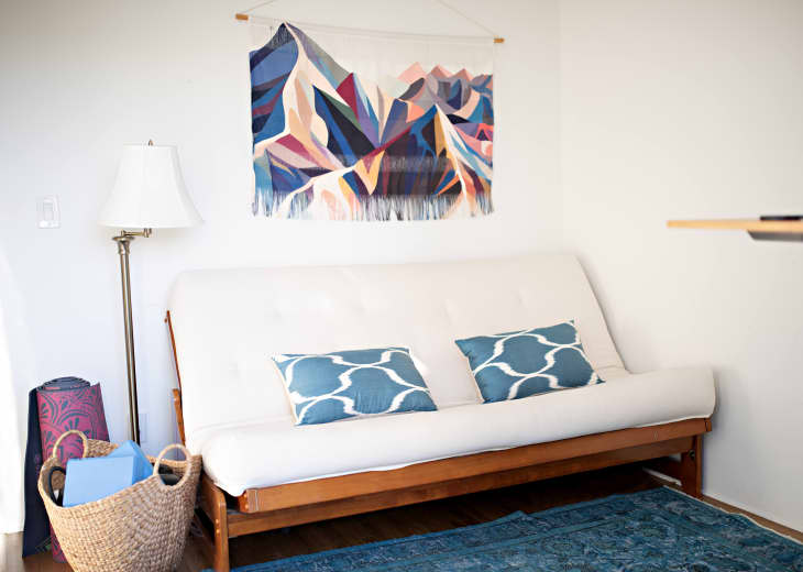 white futon with blue throw pillows and rug in white room