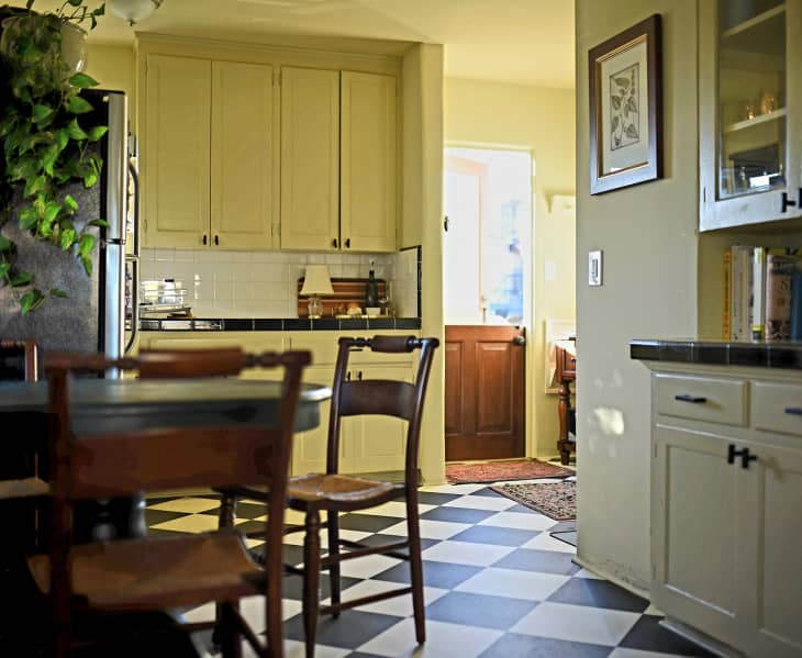 yellow kitchen with black and white checkered floor and wood furniture