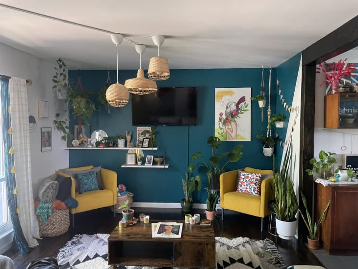 Teak and white living room with yellow armchairs and rattan pendants