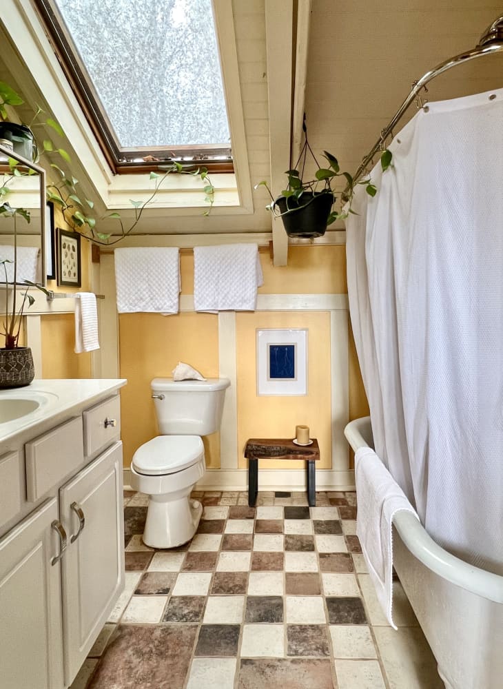 Yellow bathroom with brown and white checkered tile and a large skylight