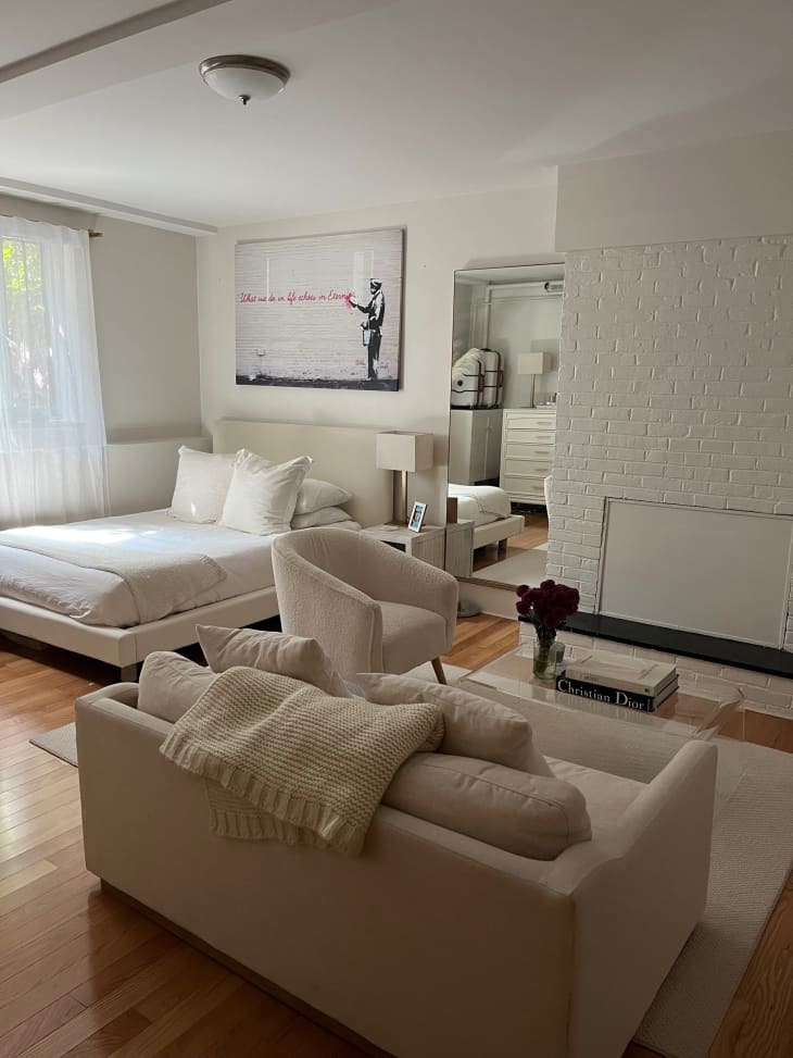 Beige sofa, beige fabric bed, white bricked off fireplace, wood floors