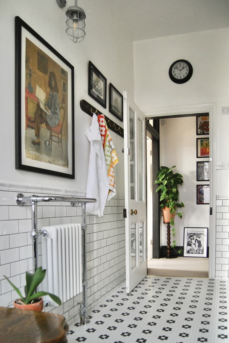 A white bathroom with a pattern tile floor and framed artwork.
