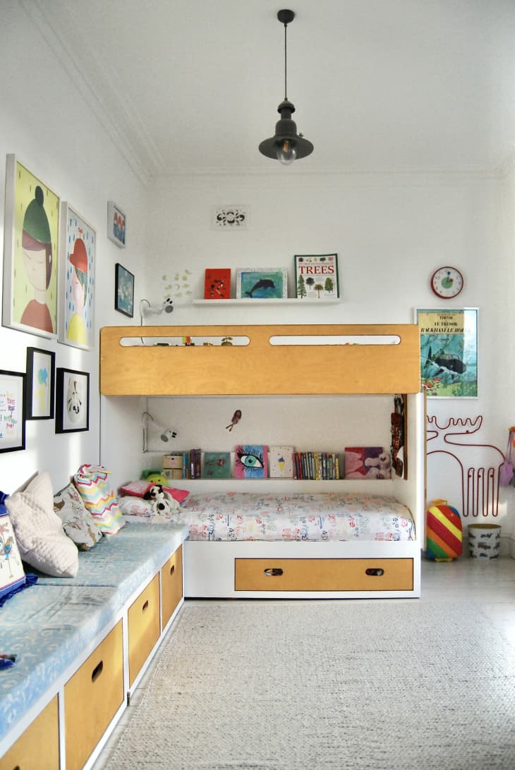 A child's white wooden bunk bed with decorative items on the wall.