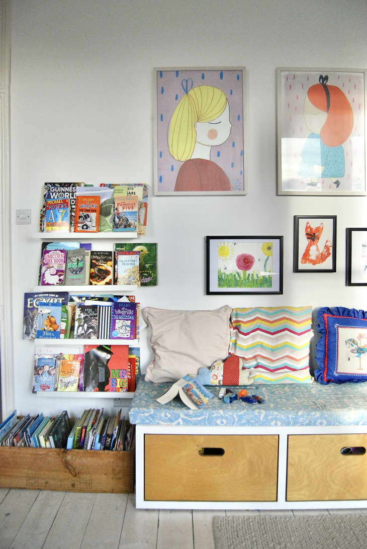 Children with bookshelf and wall of framed artwork.