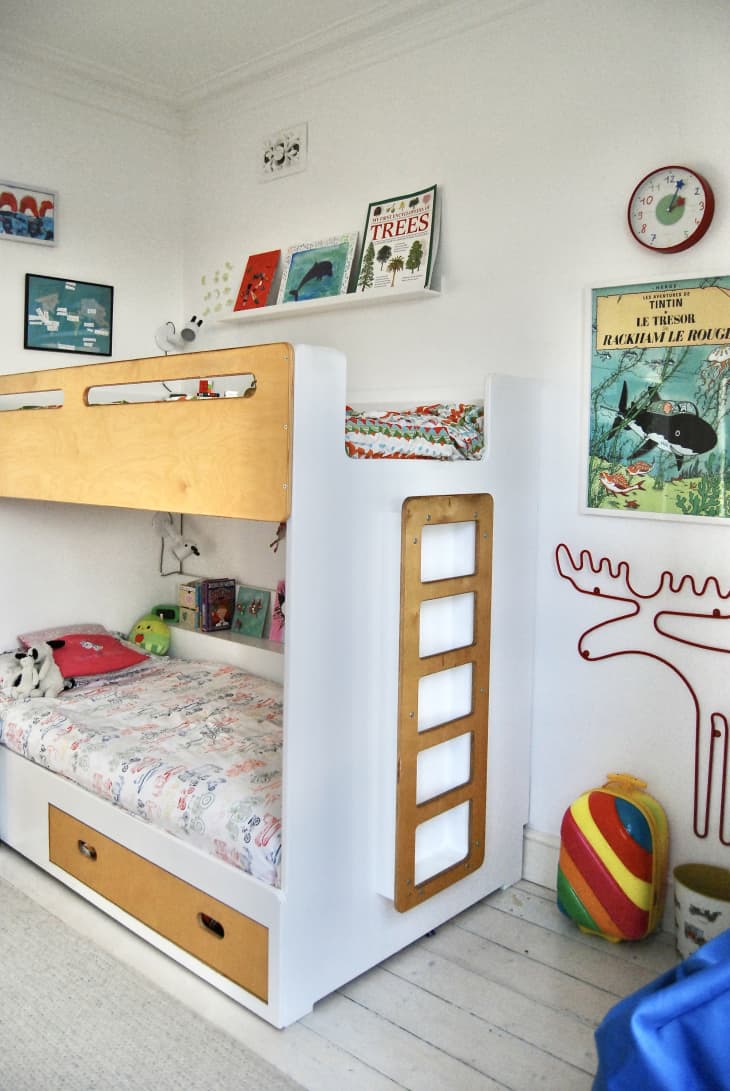 A child white wooden bunk bed with decorative items on the wall.