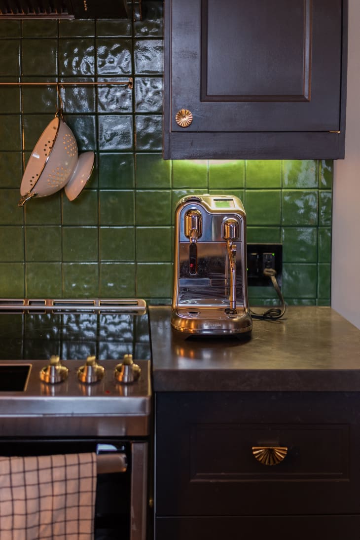 Kitchen with black cabinets and green tiled backsplash.
