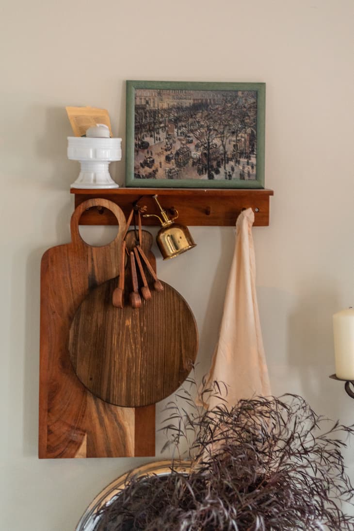 Wooden kitchen utensils hung on a rack below a framed piece of artwork.