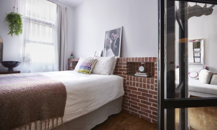 Brick walls in bedroom with neatly made bed.