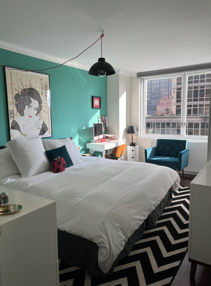 chambre bleu sarcelle et blanche avec tapis noir et blanc et grandes fenêtres à carreaux