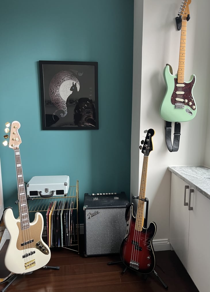 Corner of living room with teal wall with electric guitars, amp, and vinyl records