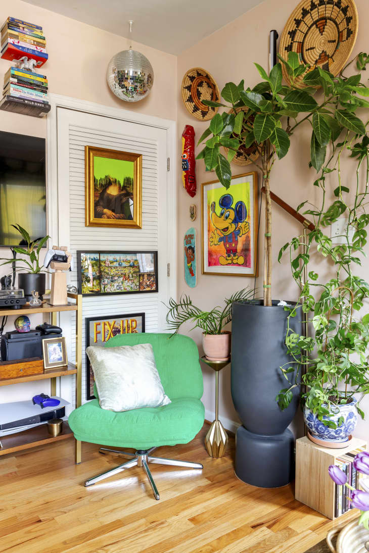 A green chair next to a framed artwork with a disco ball in the corner of a living room.