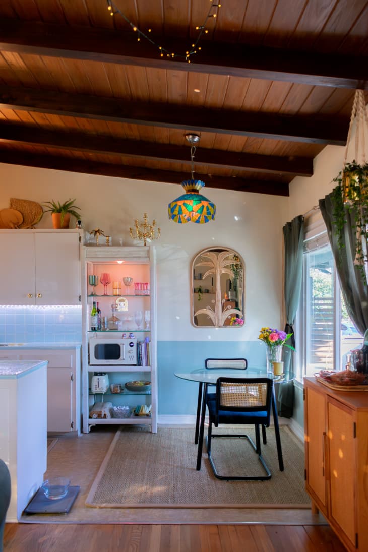 A mixed kitchen and dining room decorated with vintage glass wear and stain glass chandelier.