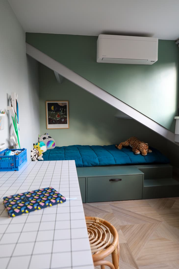 Desk and bed seen in child's bedroom with green wall.
