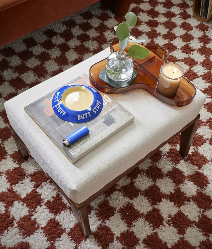 Decorative items set on ottoman stool on checkerboard rug.