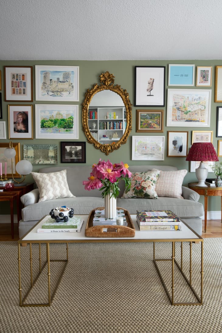 Gallery wall above gray couch with wood vintage end tables and vintage gold oval mirror