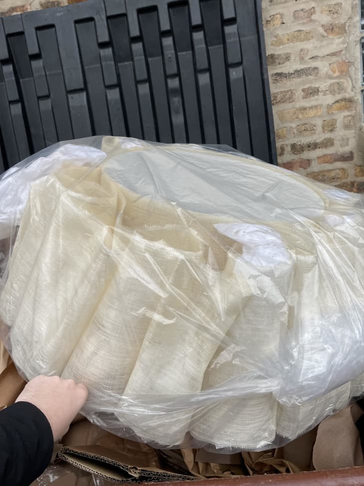 Pleated large lamp shade in plastic wrap near dumpster