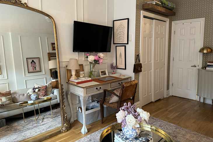 Workspace with vintage desk next to large antique mirror in studio apartment