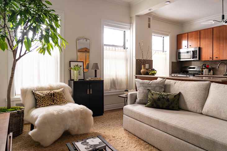 Flower arrangement on top of vintage storage unit in newly decorated living room.