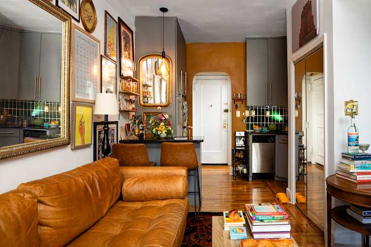 Cozy living space featuring a brown leather sofa, a bar area with glassware, and colorful artwork on the walls.