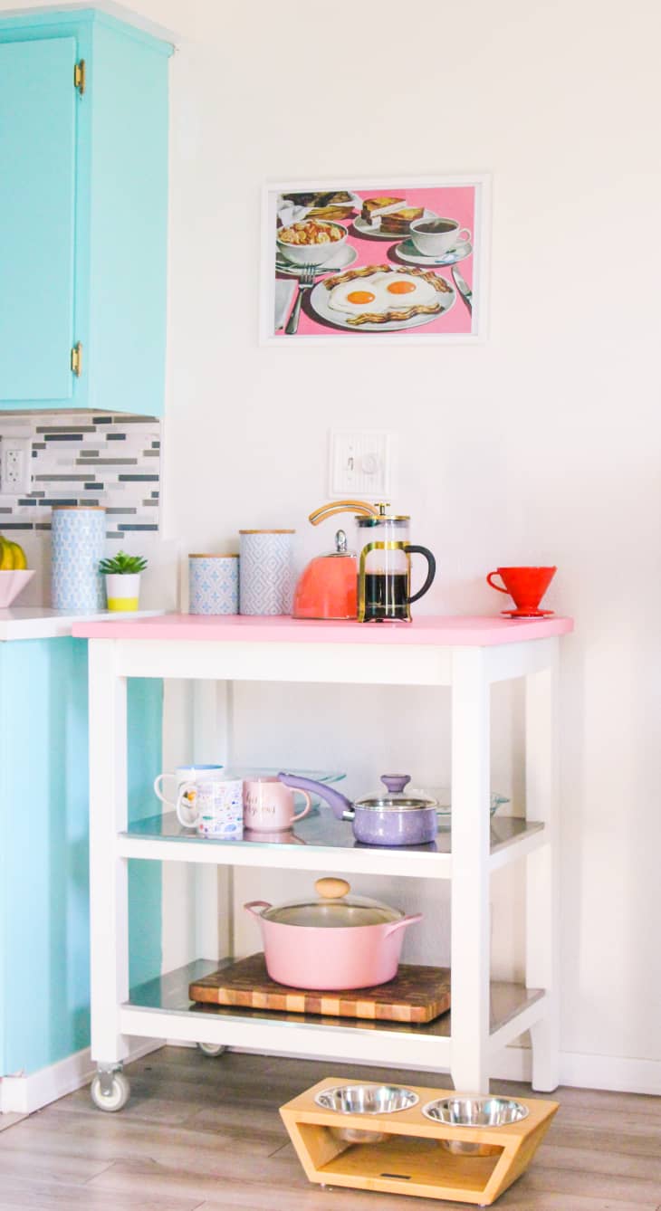 A pink kitchen island with blue cabinets and pink walls