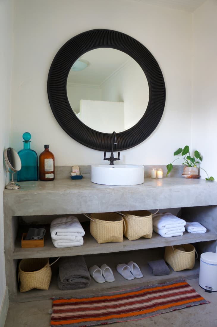 A bathroom vanity with a large black round mirror above it.