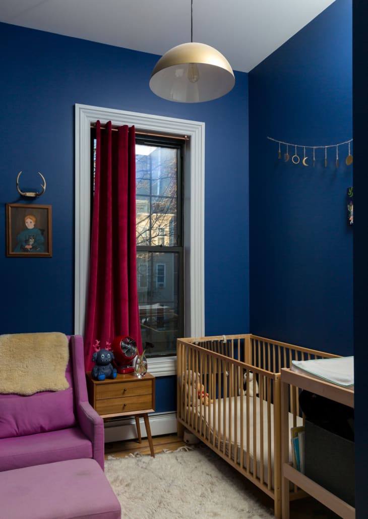 A nursery with royal blue walls and wooden crib