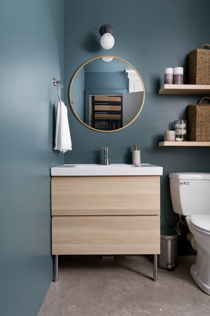 A bathroom with blue paint and Scandinavian-style vanity.