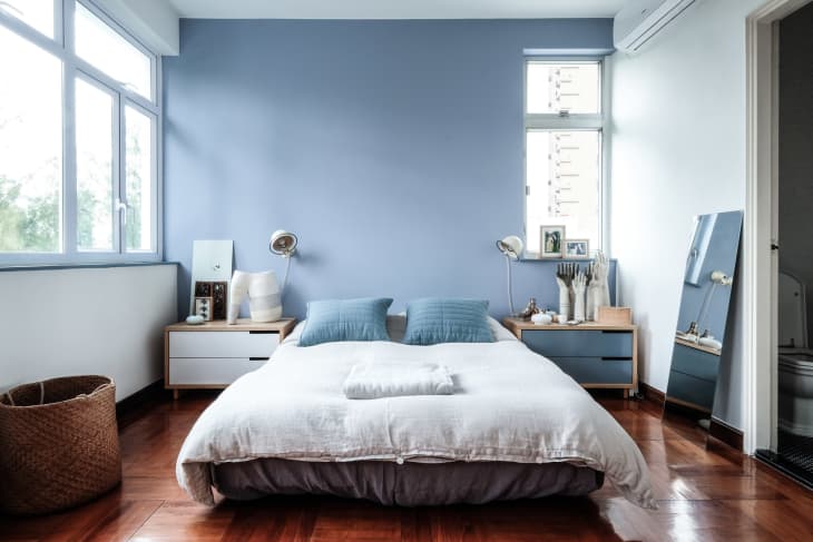 a bedroom with light blue paint and large windows