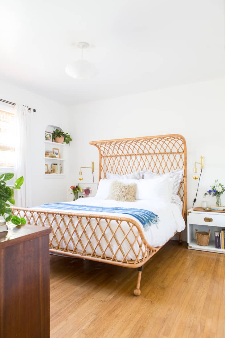 two swing-arm sconces flank a wicker bed in a bright, airy white bedroom