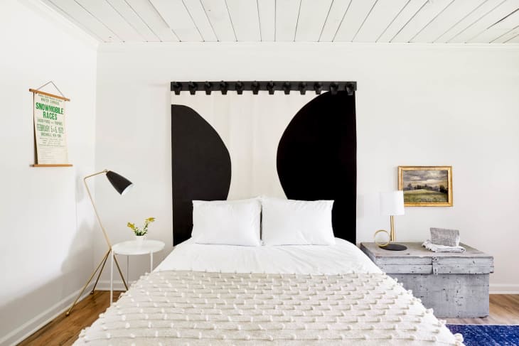 A bed with ball textures on the bedspread and black and white curtains.