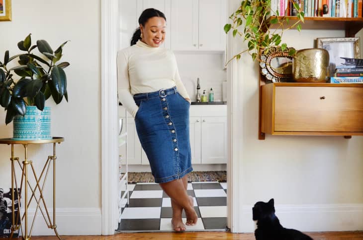 A woman standing in the hallway of her home looking down at a cat